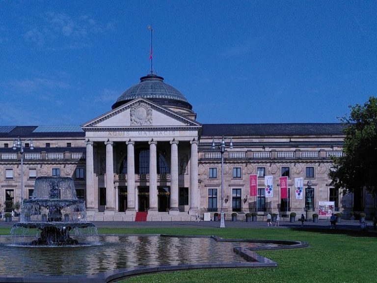 Wiesbaden historische Stadtrallye - Kurhaus und Bowling Green Historisches Gebäude mit Säulen, einem Kuppeldach und einem Brunnen im Vordergrund.
