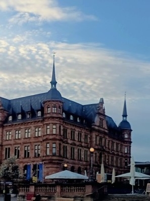 Neues Rathaus - Wiesbaden Historisches Gebäude mit Türmchen und blauem Himmel im Hintergrund.