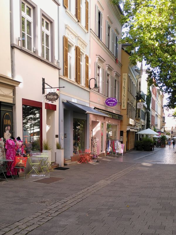 Stadtrallye Wiesbaden - Altstadt mit malerischen Gässchen Verkehrsberuhigte Straße mit bunten Gebäuden und Geschäften, umgeben von Pflanzen.